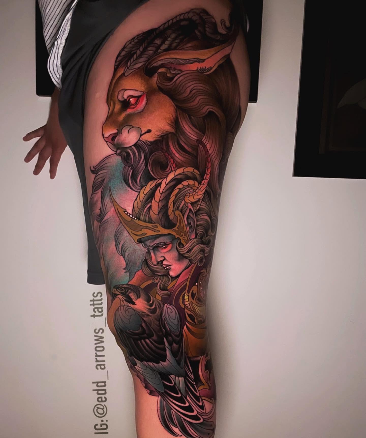 Thigh tattoo of a red-eyed hare above a helmed valkyrie with a falcon, neo-traditional color