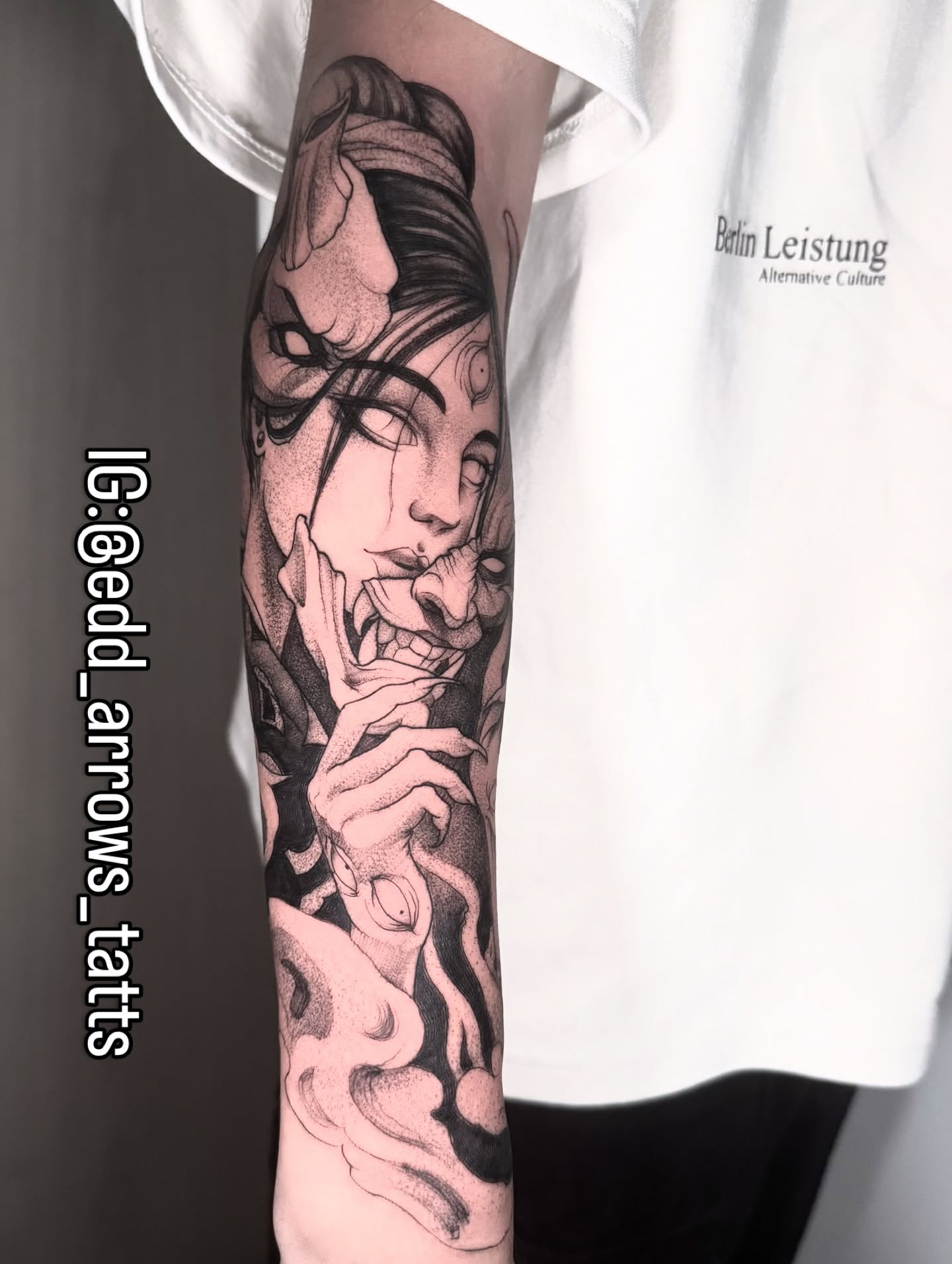 Blackwork forearm sleeve of a woman's face beside a grinning hannya mask, fine dotwork shading