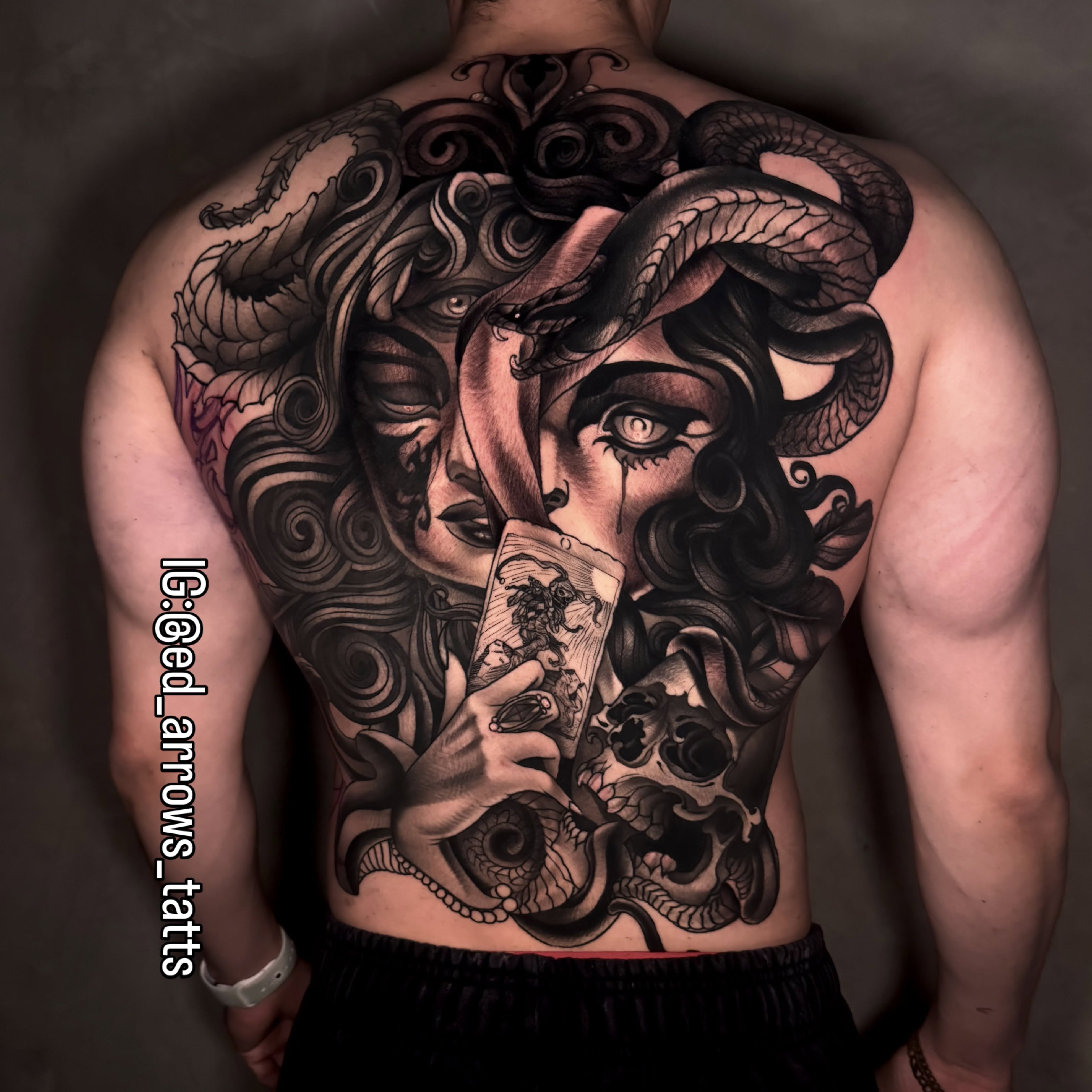 Full-back black and grey tattoo of Medusa holding a tarot card, snakes woven through her hair
